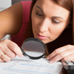 Mulher analisando extrato bancário com lupa